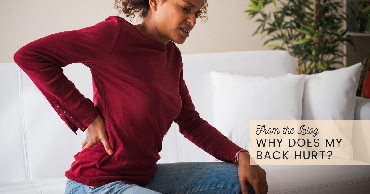 Spine doctor pointing to sore spot on woman's lower back in office.