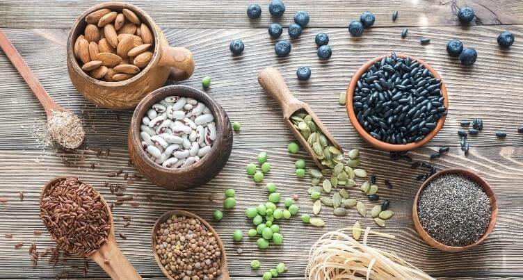 Various high fiber foods including oatmeal, berries, beans, nuts, seeds.