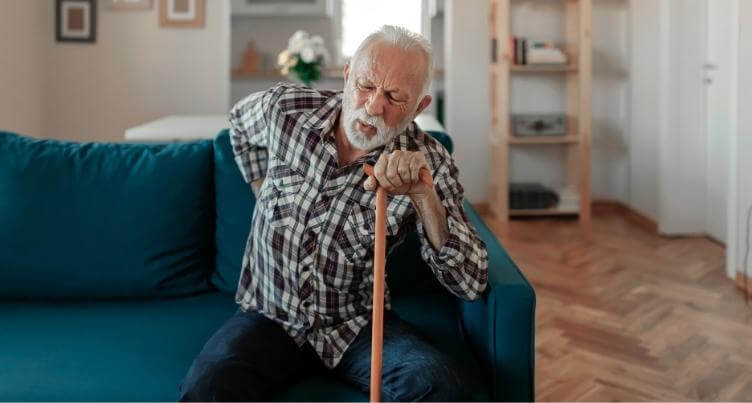 Man looking stressed and holding her back in pain.