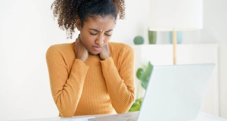 Woman sitting at a desk slouching with poor posture.
