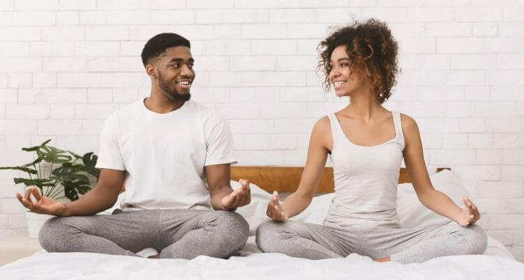 Woman and man meditating by a Christmas tree.
