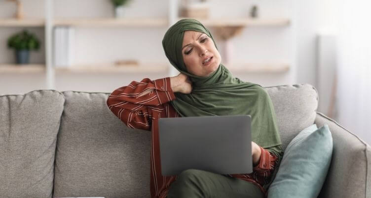 Person with hand on sore neck, looking uncomfortable